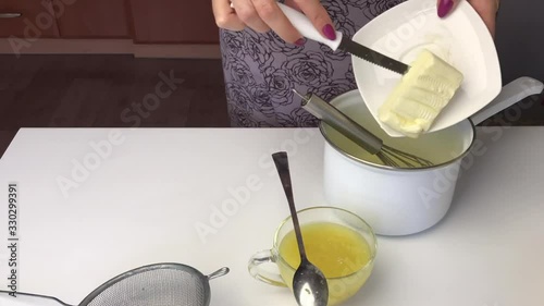 Girl mixes ingredients for lemon kurd in a saucepan. After that, he puts it on a gas stove and stirs during cooking. photo