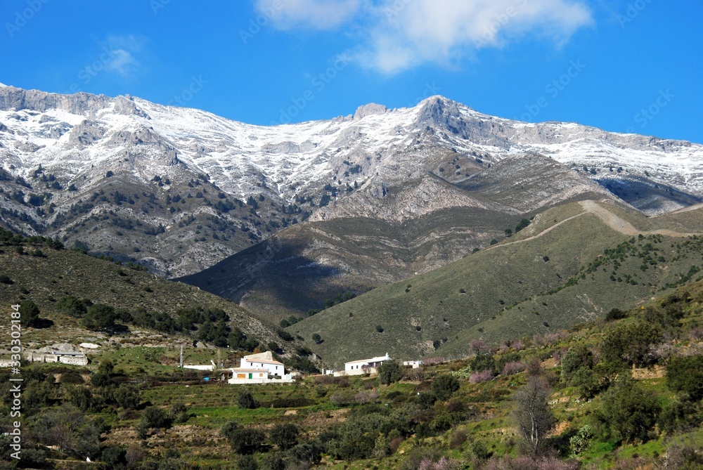Country houses snow capped mountains to the rear, Sedella, Spain.