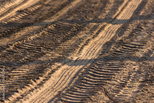 Tractor tyre tracks on a countryside dirt road at sunset photo