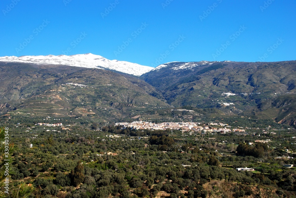 View of the town and countryside in the Vale of Lecrin with views towards the snow capped Sierra Nevada mountains, Orgiva, Spain. View of the town and countryside in the Vale of Lecrin with views towards the snow capped Sierra Nevada mountains, Orgiva, Spain.