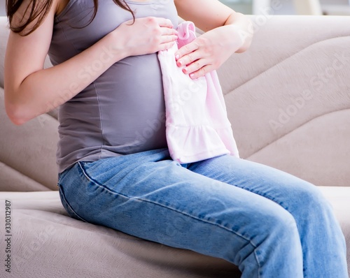 Pregnant woman with a belly tummy sitting on a sofa at home