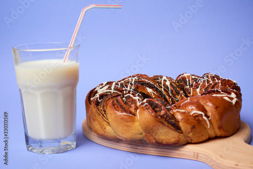 Braided roll with poppy seeds and cinnamon on yellow background. Top view photo