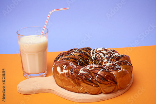 Braided roll with poppy seeds and cinnamon on yellow background. Top view photo