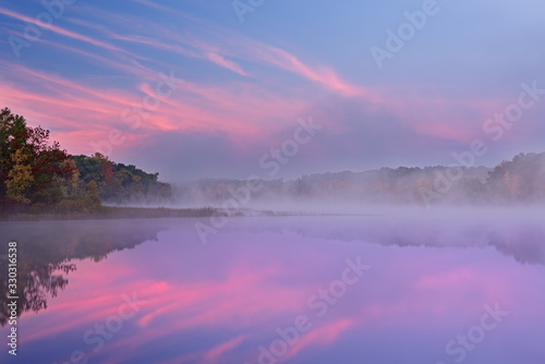 Autumn landscape at dawn of the shoreline of Deep Lake with mirrored reflections in calm water  Yankee Springs State Park  Michigan  USA