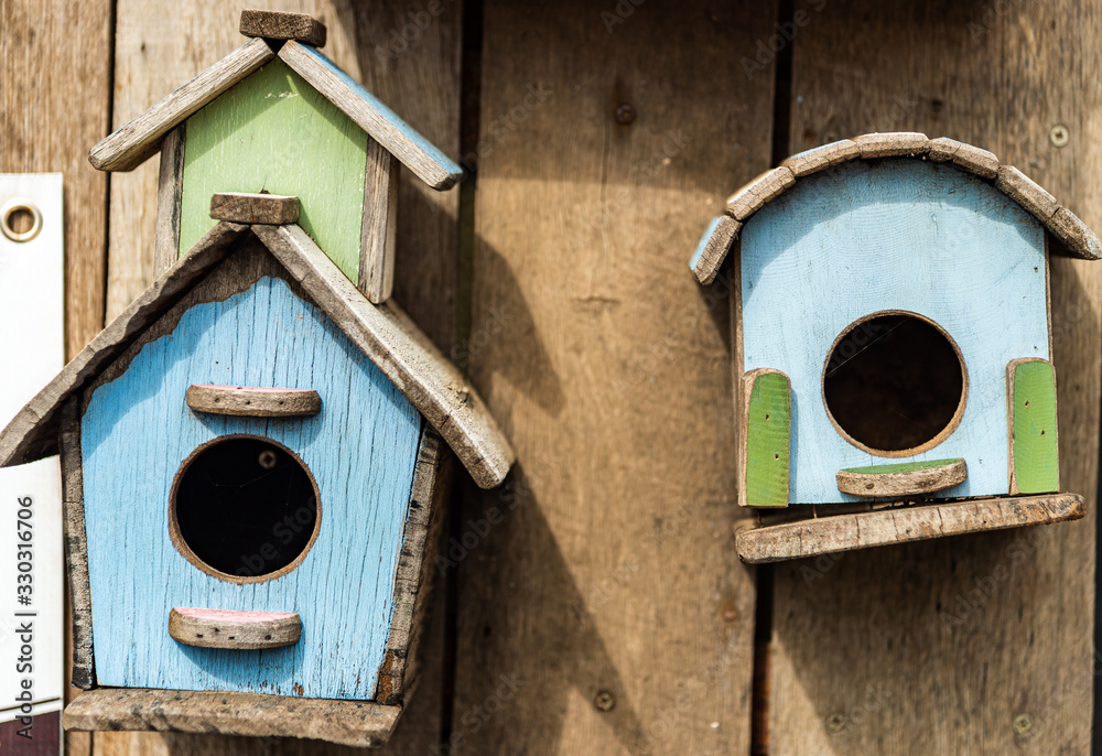 Three small handmade wood birdhouses with wooden wall background