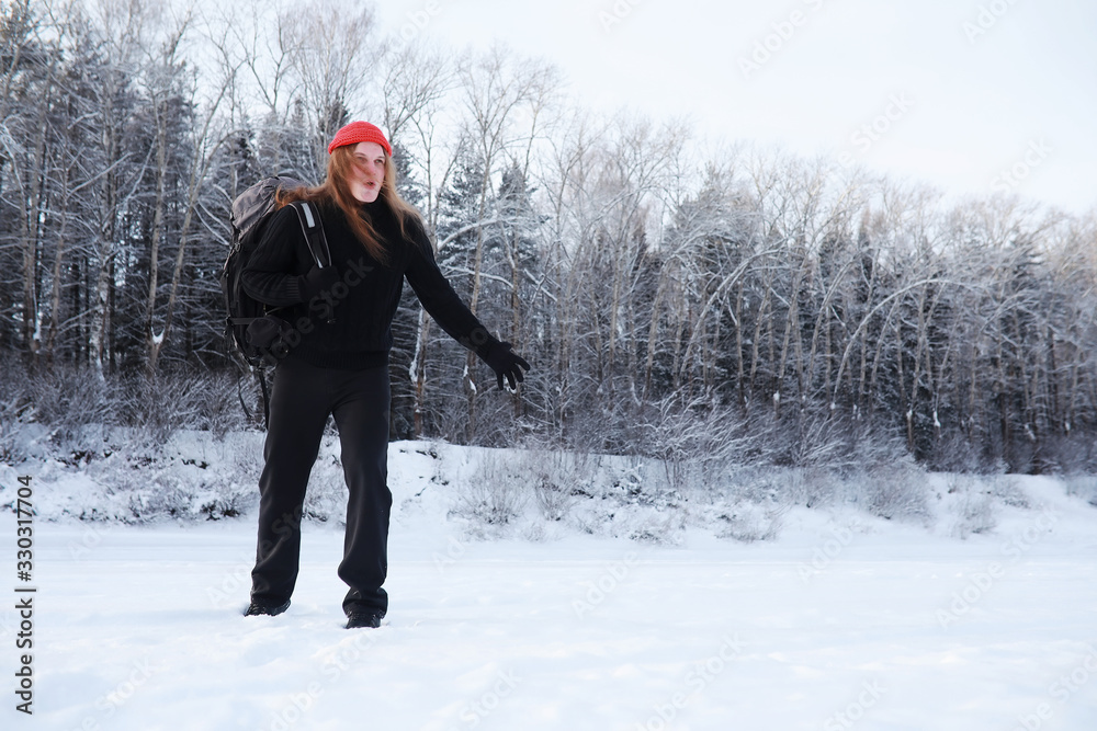 A man travels with a backpack. Winter hike in the forest. Tourist on a walk in the winter in the park.