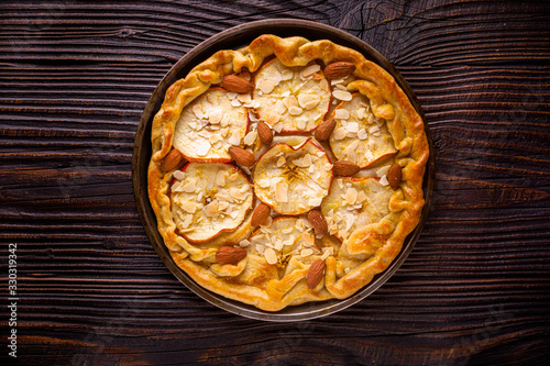 crispy apple galette with almonds on rustic wooden background