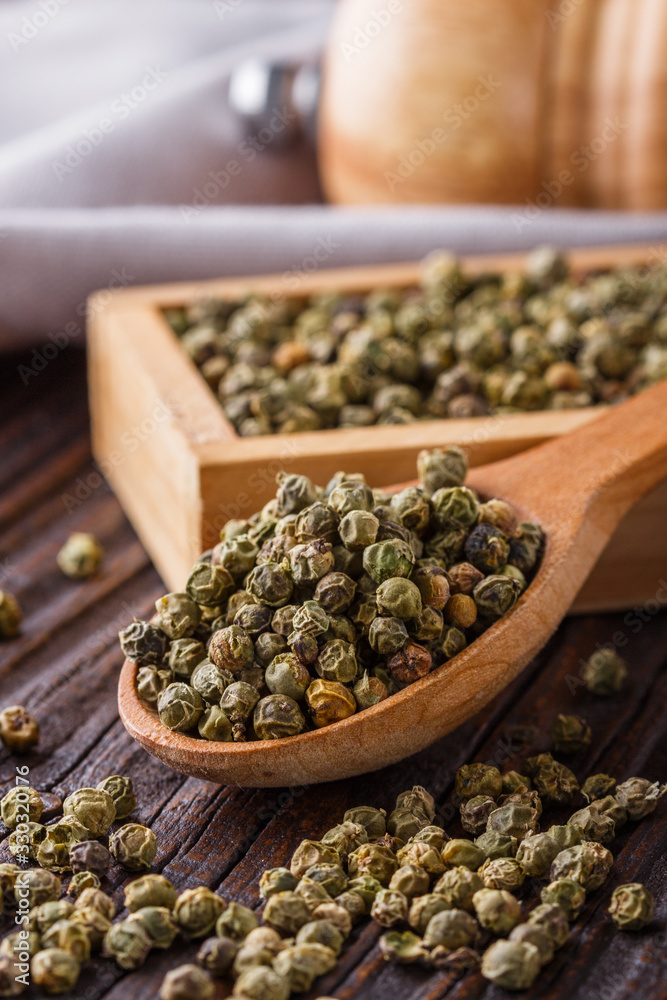 green peppercorns in wooden scoop on rustic background green peppercorns in wooden scoop on rustic background