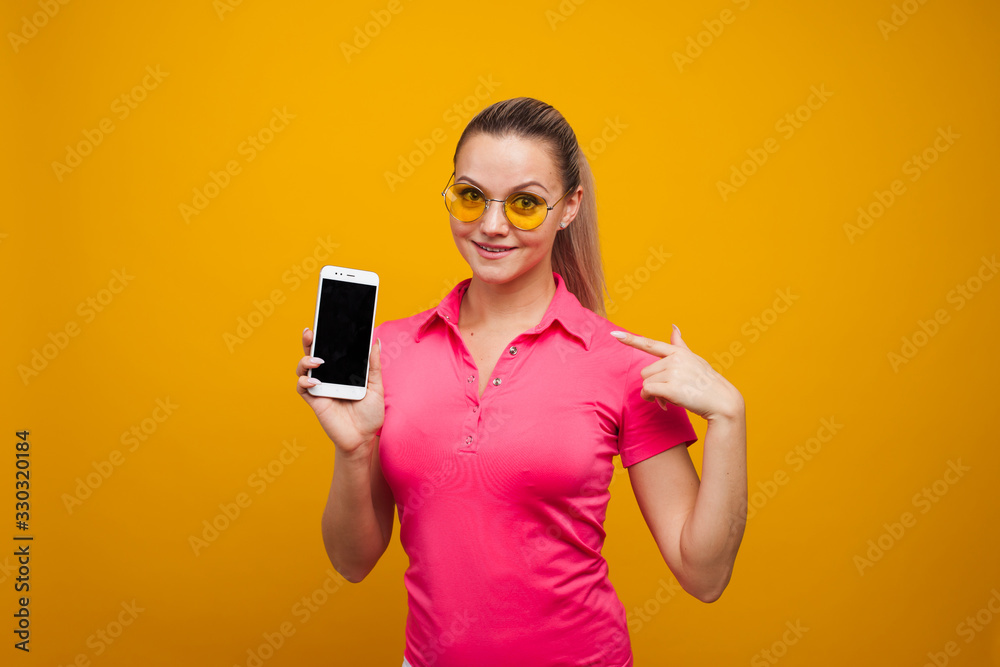 Bright and positive young woman with smartphone on yellow background. The girl uses a smartphone
