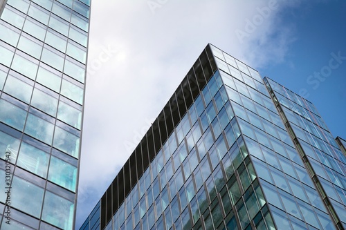 Modern curtain wall made of glass and steel. Blue sky and clouds reflected in windows of modern office building. 