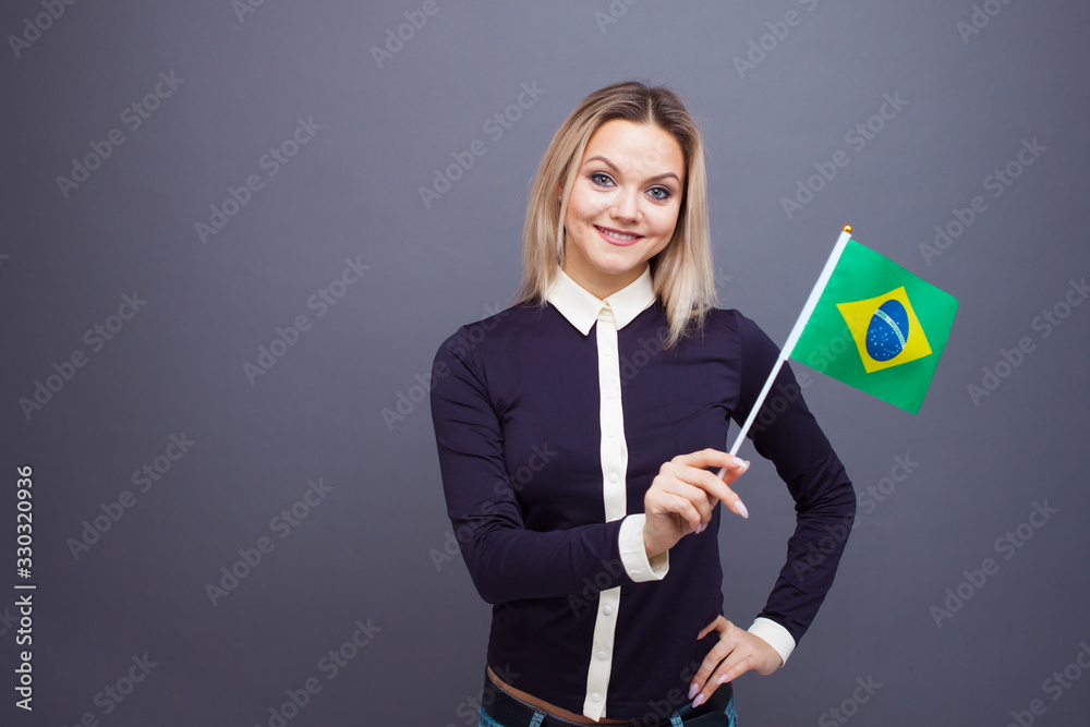 Immigration and the study of foreign languages, concept. A young smiling woman with a Brazil flag in her hand. Immigration and the study of foreign languages, concept. A young smiling woman with a Brazil flag in her hand.
