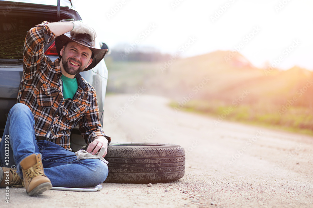 Man is sitting on the road by the car