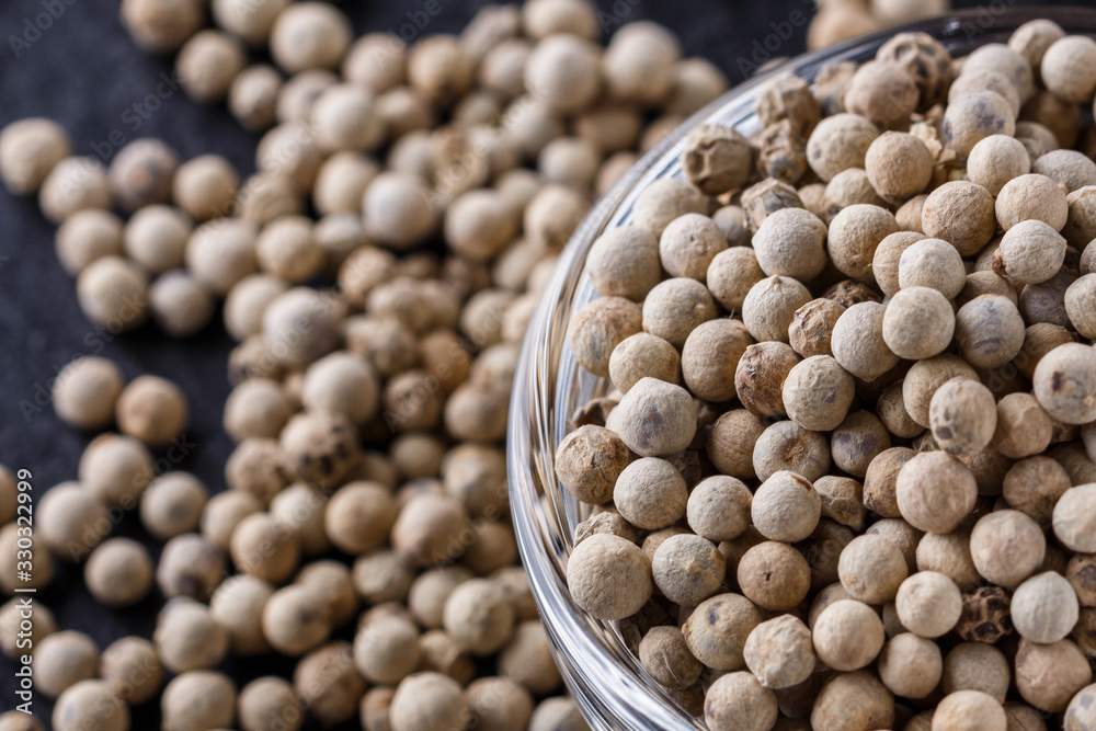 white peppercorns in glass bowl on stone background white peppercorns in glass bowl on stone background