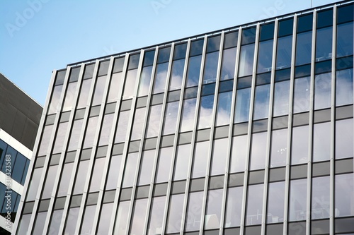 Modern curtain wall made of glass and steel. Blue sky and clouds reflected in windows of modern office building. 