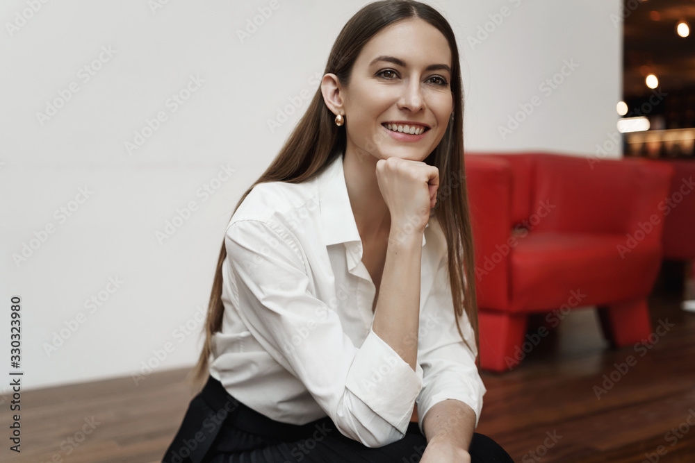 Cheerful attractive female entrepreneur sitting on red armchair, smiling and laughing, have business meeting, introduce her design project for company team lead, having conversation Cheerful attractive female entrepreneur sitting on red armchair, smiling and laughing, have business meeting, introduce her design project for company team lead, having conversation