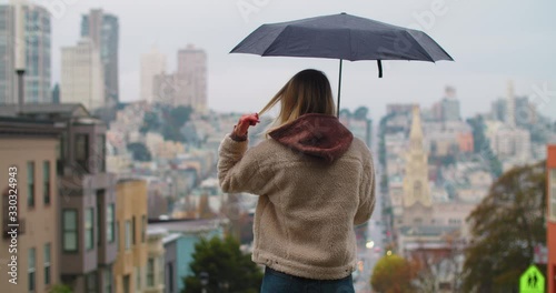 A young woman holding an umbrella on a street in San Francisco. photo