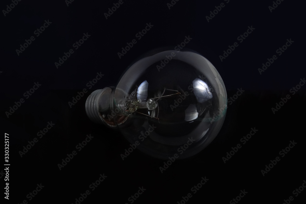 Incandescent light bulb on a black background. Front view.
