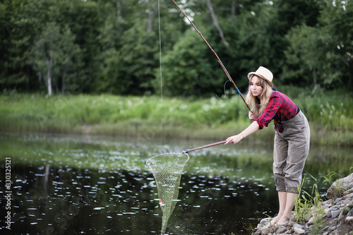 Girl by the river with a fishing rod