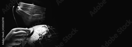 Kid hold globe put stethoscope on sphere, face covered in mask on black horizontal background. Ecological problems disasters. COVID-19 pandemic infection disease concept image, copy space for text photo