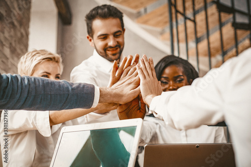 Diverse Business Team Giving High Five At Meeting In Modern Office, Multi Ethnic Group Of White Collar Workers Celebrating Successful Deal, Team Building Concept, Toned Image