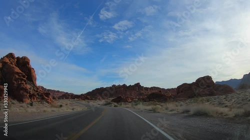 4K. POV view of car driving on road of highway at cloudy day in USA. Drive on an empty road in the dark evening. Asphalt with yellow line at new road in Valley of Fire. Nevada state.