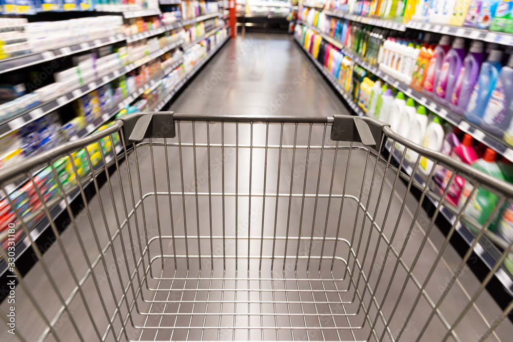 Shopping trolley cart moving in supermarket with motion blur aisle background Shopping trolley cart moving in supermarket with motion blur aisle background