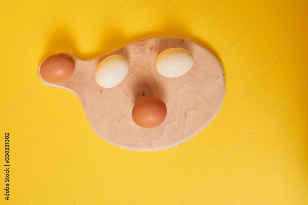 Fototapeta premium Eggs on a yellow background. Chicken eggs on a wooden board