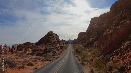 4K. POV view of car driving on road of highway at day in USA. Drive on an empty road in the dark evening. Asphalt with yellow line at new road in Valley of Fire. Nevada state.