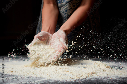 Baker prepares homemade cakes. Professional Female cook sprinkles dough with flour, prepared for baked bread
