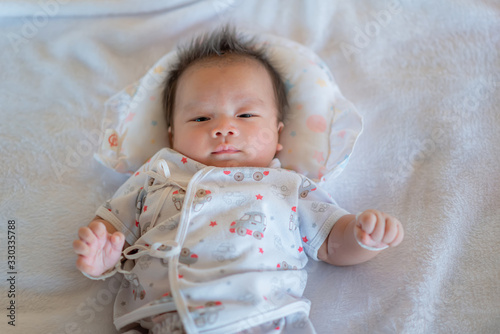 Newborn baby lying on a soft white mattress, smiling happily.