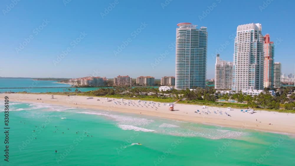 Drone flying forward near Miami Beach, South Beach, Florida. Cinematic video of a luxury resort in Miami South Beach. Surfers ride surfs in the ocean waves. Miami Beach on a sunny day, aerial view Drone flying forward near Miami Beach, South Beach, Florida. Cinematic video of a luxury resort in Miami South Beach. Surfers ride surfs in the ocean waves. Miami Beach on a sunny day, aerial view
