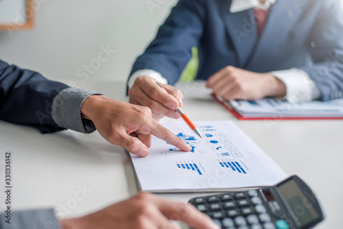 Businessman pointing to a document graph during a business meeting.