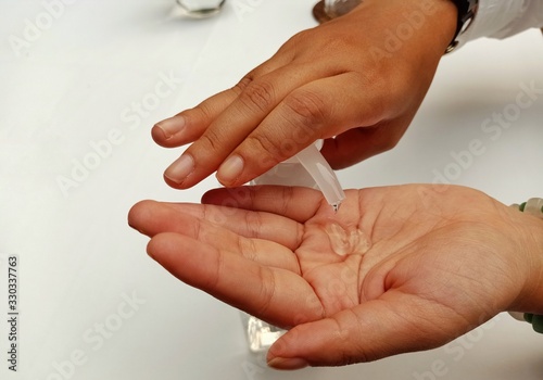 A young woman's hand is using a gel to wash her hands and clean her to prevent illness.