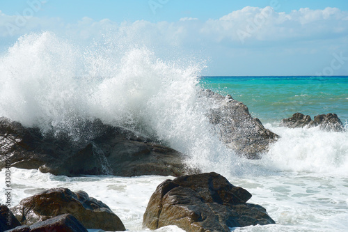 Sea waves are bouncing hard onto rocks.