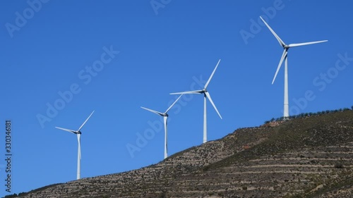 Molinos de viento en un parque eólico del sureste de España, cuatro aerogeneradores se mueven por el viento  sobre un cielo azul