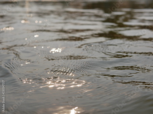 Close up and selective focus of flowing river surface with refelection of the evening sun