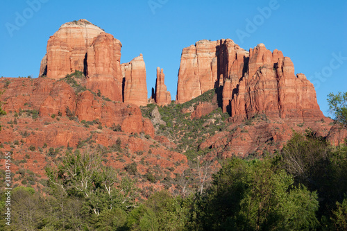 Cathedral Rock above green summer foliage near Sedona, Arizona on cloudless summer day.
