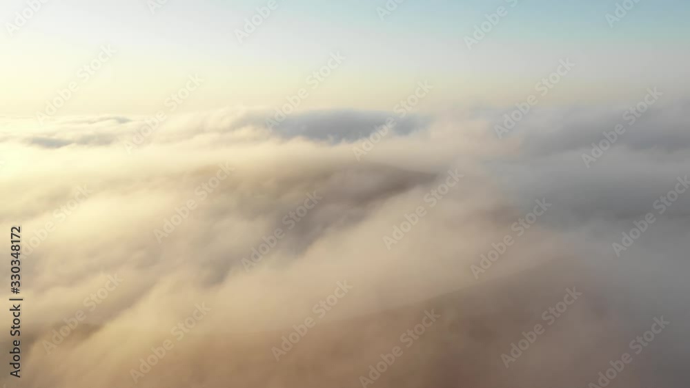 Aerial view of a drone flying among thick fog clouds surrounding massive sand dunes in the Empty Quarter at dawn. Liwa desert, Abu Dhabi, United Arab Emirates. Aerial view of a drone flying among thick fog clouds surrounding massive sand dunes in the Empty Quarter at dawn. Liwa desert, Abu Dhabi, United Arab Emirates.