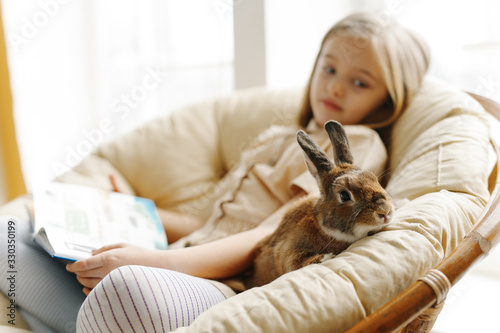 cute little girl study on the sofa in the company of rabbit 