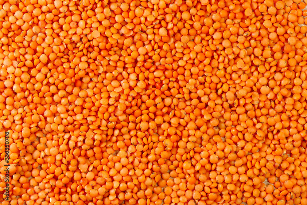 Food background. Textured background of red lentil grains. Abstract natural orange background. Top view on lentil grains. Close-up, horizontal, top view, free space. Agriculture concept.