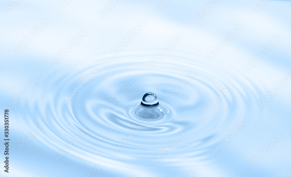 Water drop falling into water making splash and ripples. Light blue nature background. Water drop falling into water making splash and ripples. Light blue nature background.
