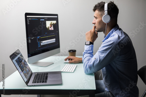 Confident man video editor works with footage in creative office studio. photo