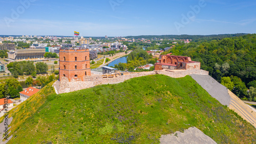 Beautiful panoramic aerial view photo from flying drone on Gediminas castle in capital Vilnius of Lithuania with Lithuanian flag on the tower and skyline of city center in the background. (series)