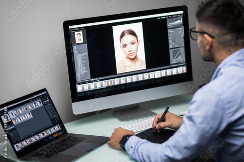 Young man designer editing photo on computer in office