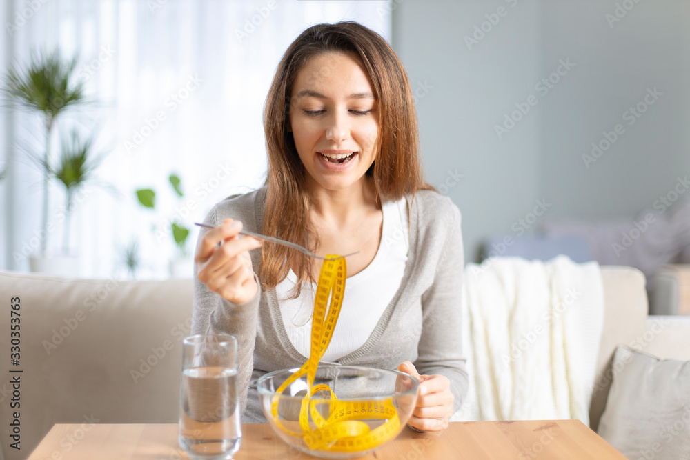 Young woman holding fork with measuring tapes. Young woman holding fork with measuring tapes.