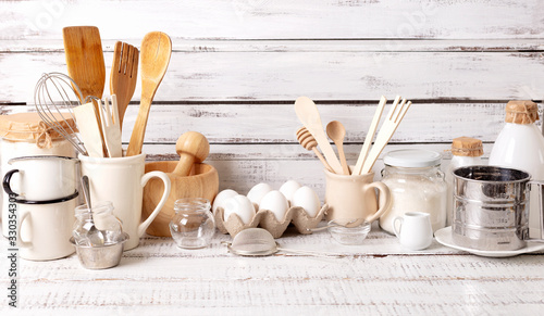 Baking kitchenware and baking products on white wooden background.