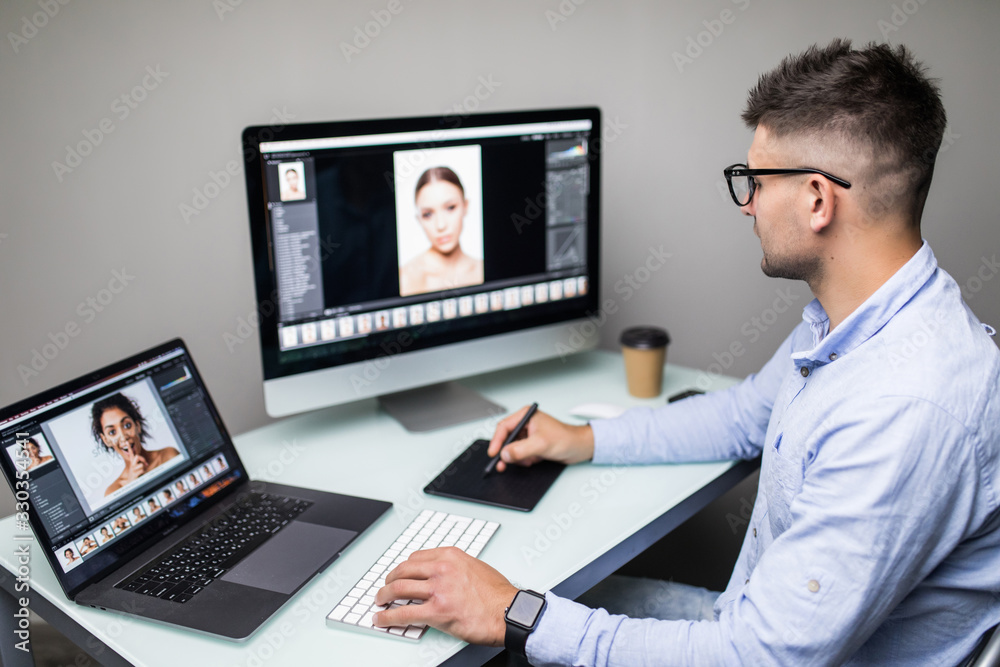 Side view of a man photo editor using graphics tablet in a bright office Side view of a man photo editor using graphics tablet in a bright office