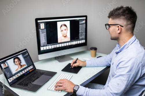 Side view of a man photo editor using graphics tablet in a bright office