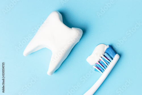 Toothbrush with toothpaste and white tooth on blue background  concept of healthy oral cavity.