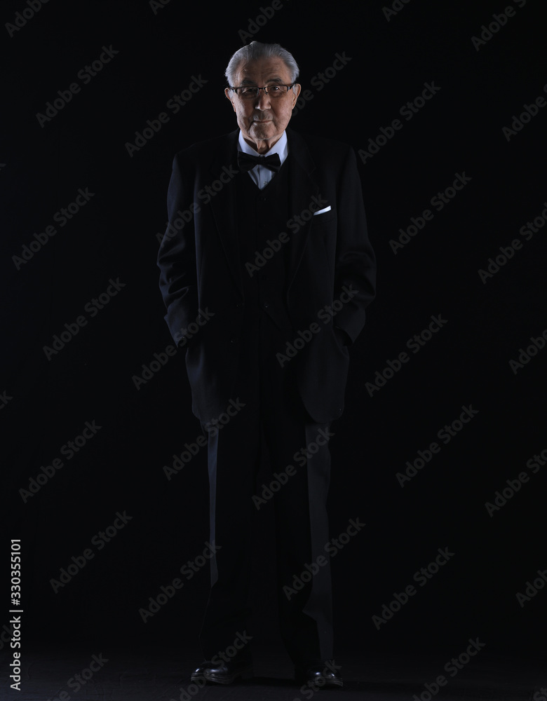 Fototapeta premium old man in a black suit on a black studio background